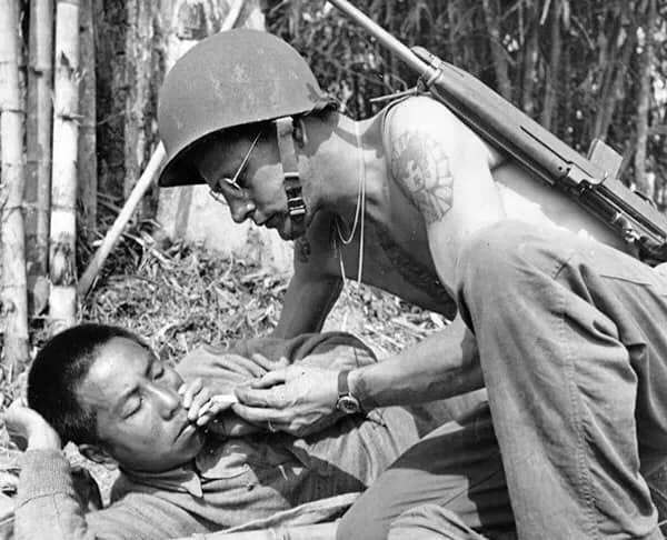 1944年，缅北，一位美军步兵正为负伤的中国士兵点烟。 