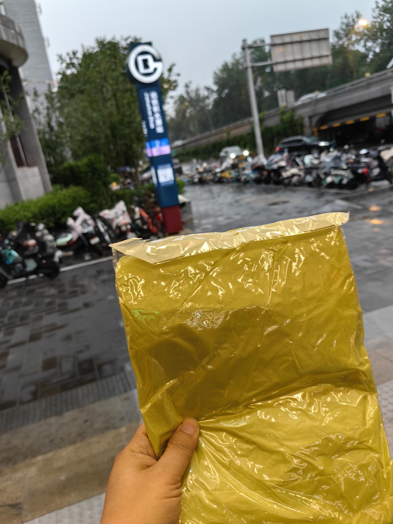 京城突降大雨，人员聚集地铁站口。地铁站人员给避雨的人们免费发雨衣。虽有一定成本，