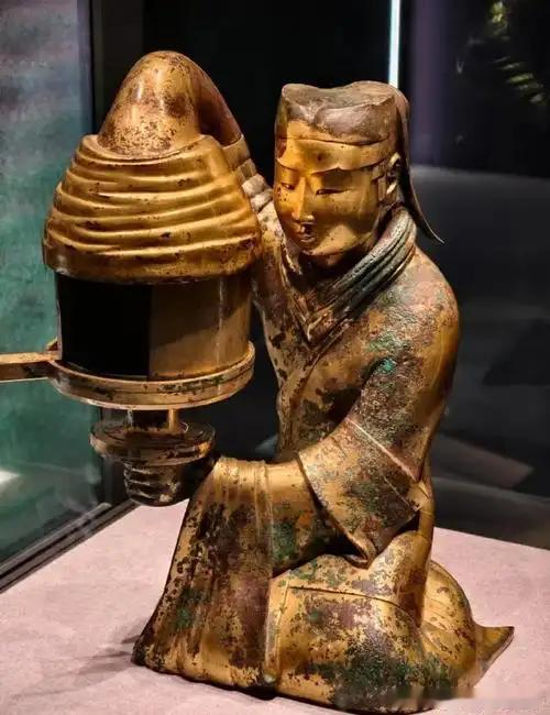 【西汉鎏金长信宫灯】出土于满城汉墓，为青铜通体鎏金质地，造型是跪坐宫女持灯模样。