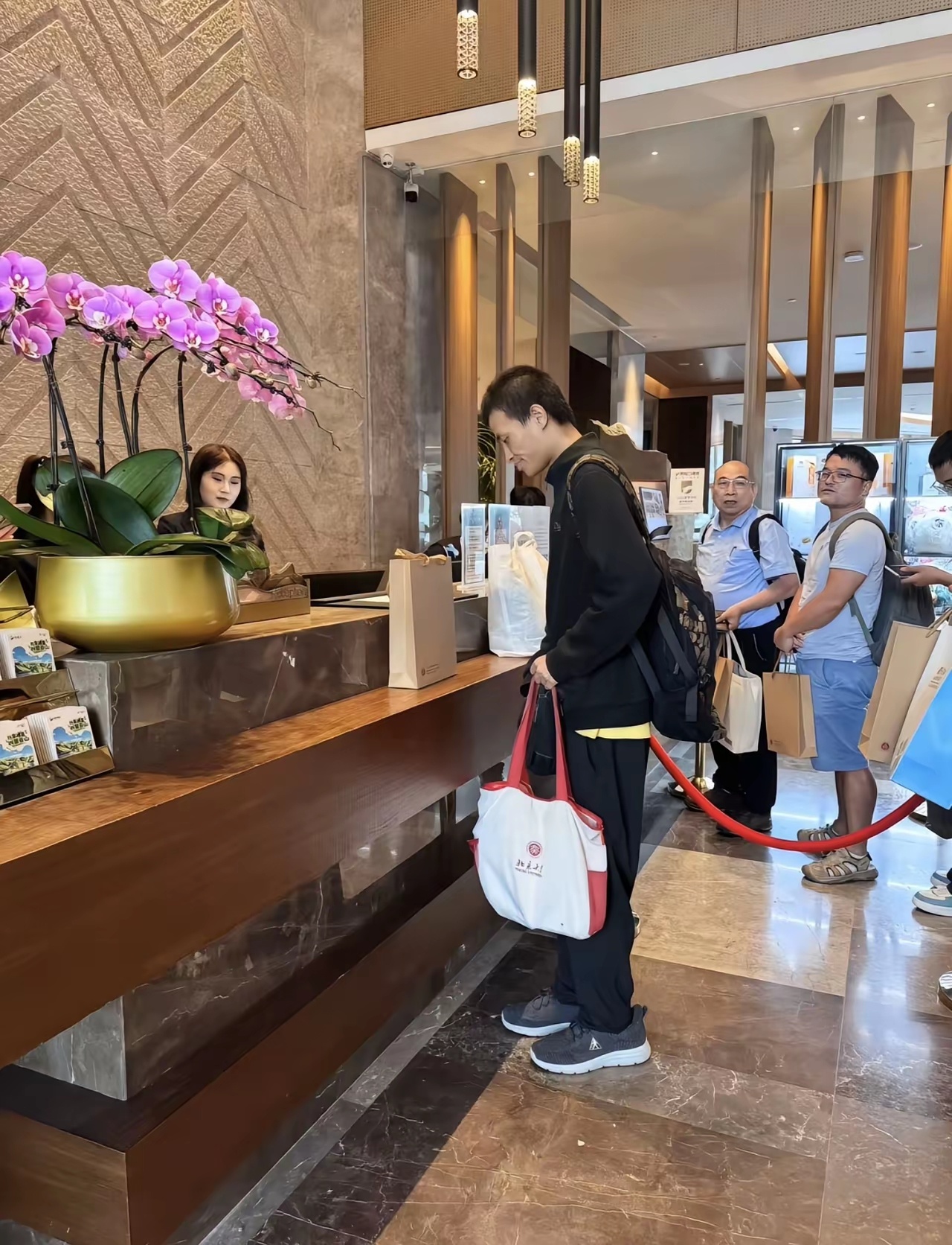 8月14日，“韦神”在崇礼酒店大堂办理入住，背着大包参加数学活动，没有行李箱，拿