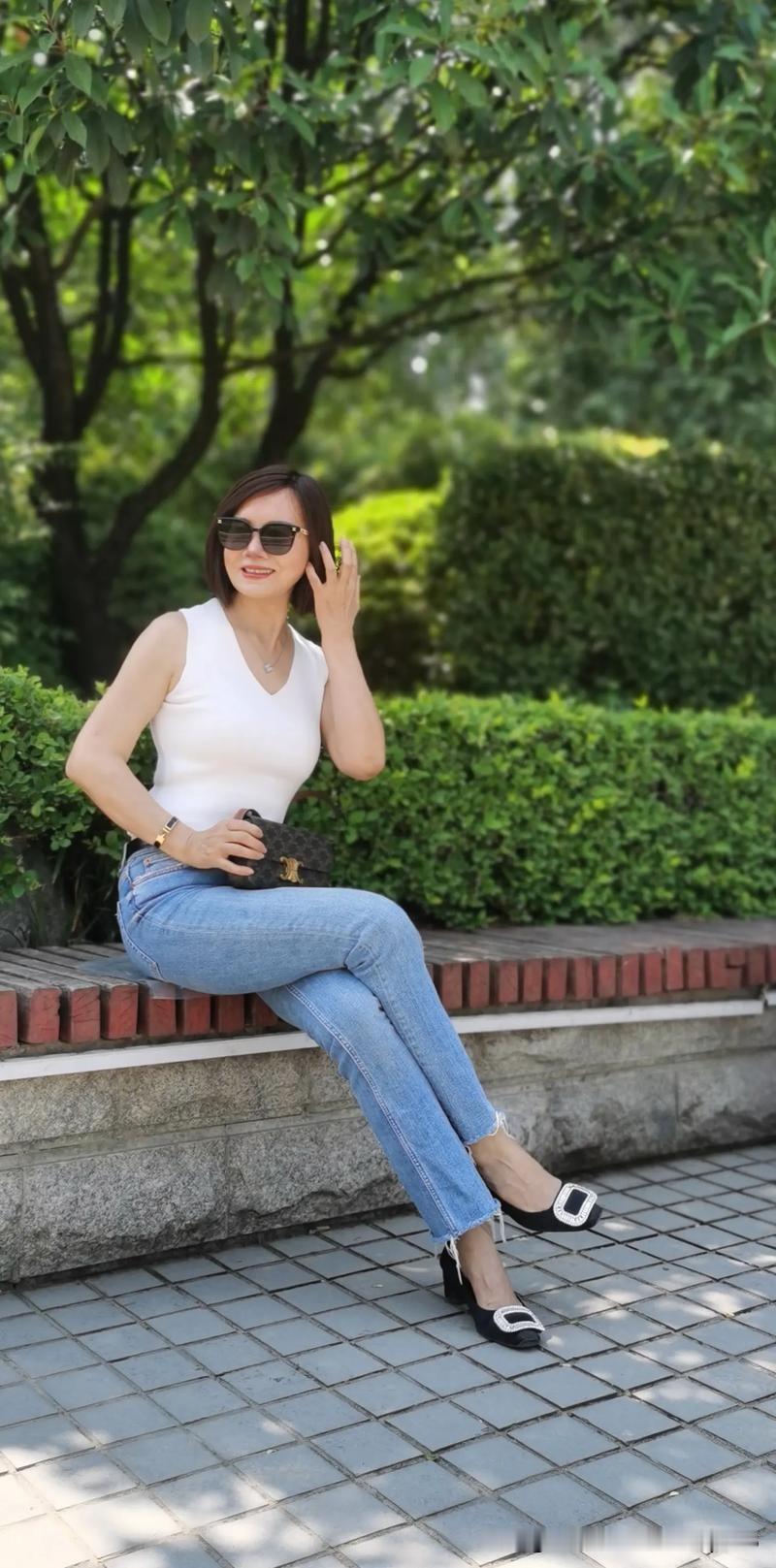 晒图笔记大赛一个穿白色上衣和牛仔裤的女士坐在长椅上，尽显女士优雅之风采。