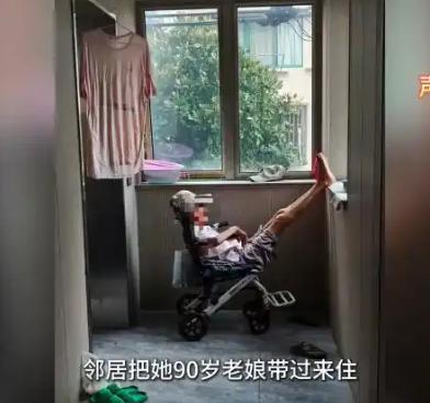 上海一处老居民楼的二楼楼道里，靠电梯间的位置摆着一张轮椅。轮椅上坐着一位90岁的