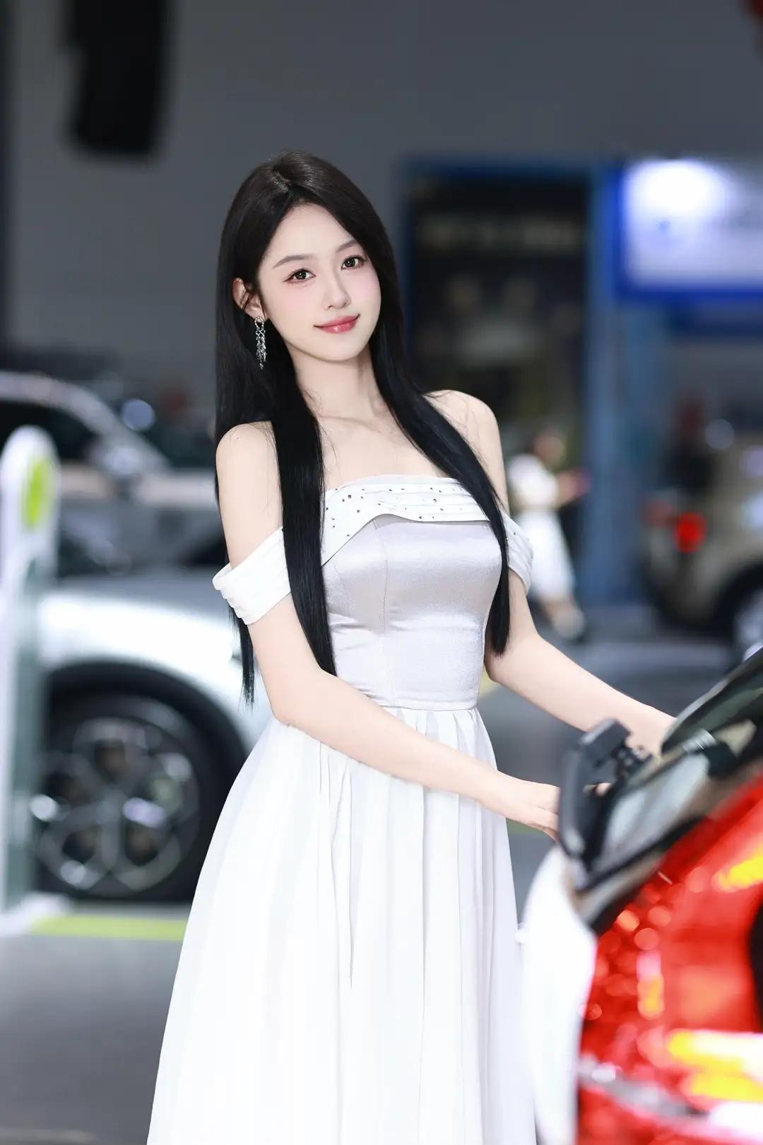《光影中的自信》
在柔和而明亮的光线下，她宛如一颗璀璨的明珠，静静地绽放在车展的