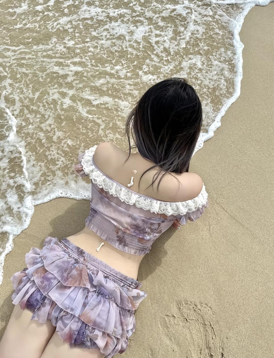 一位姑娘躺在沙滩上，背对着海浪。