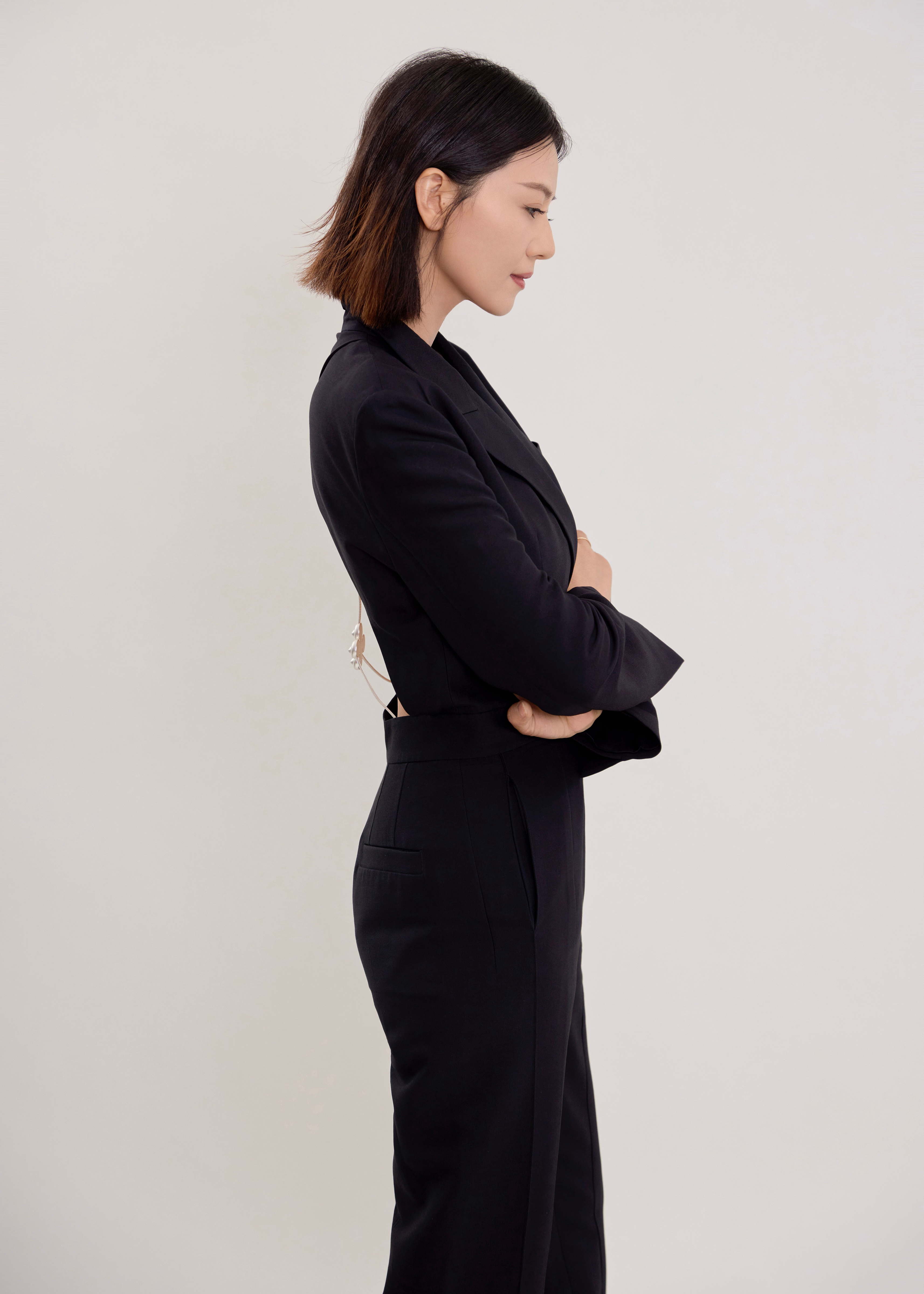 身着黑色露背西装套装，将干练与性感巧妙融合。利落的剪裁勾勒出优雅身形，背部的镂空