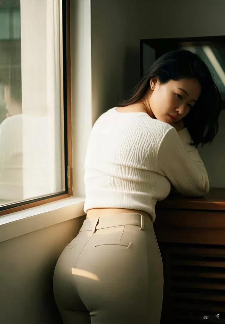 女子站在窗边，背后是温暖的阳光，光线如同金色的纱幔，轻轻地披在她的身上。她的姿态