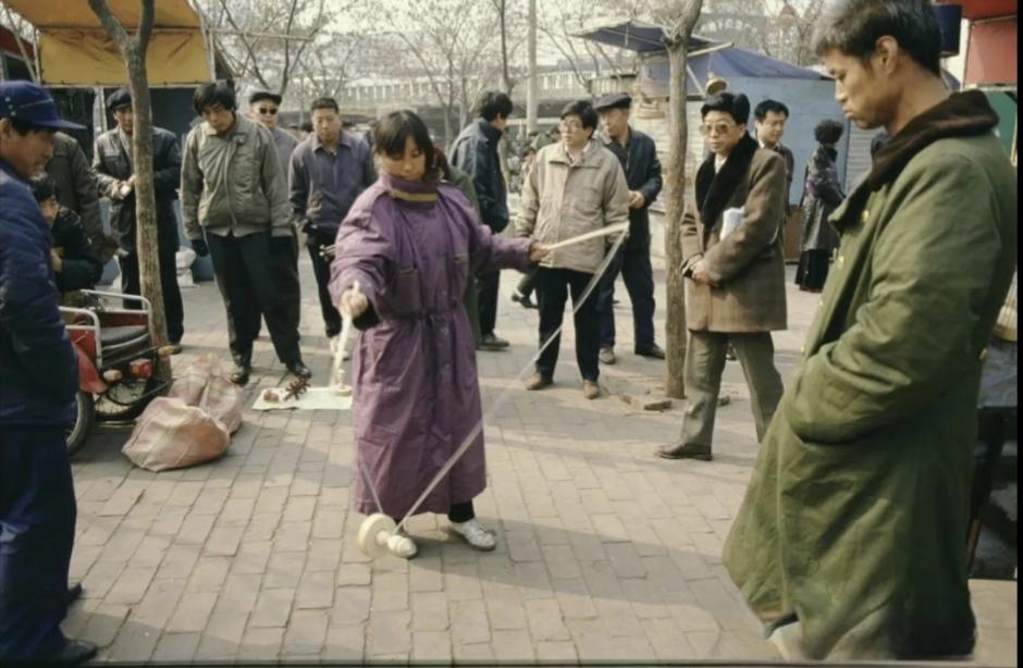 怀旧老照片共享上世纪九十年代北京街头，一女的在抖空竹，一群男的在围观！