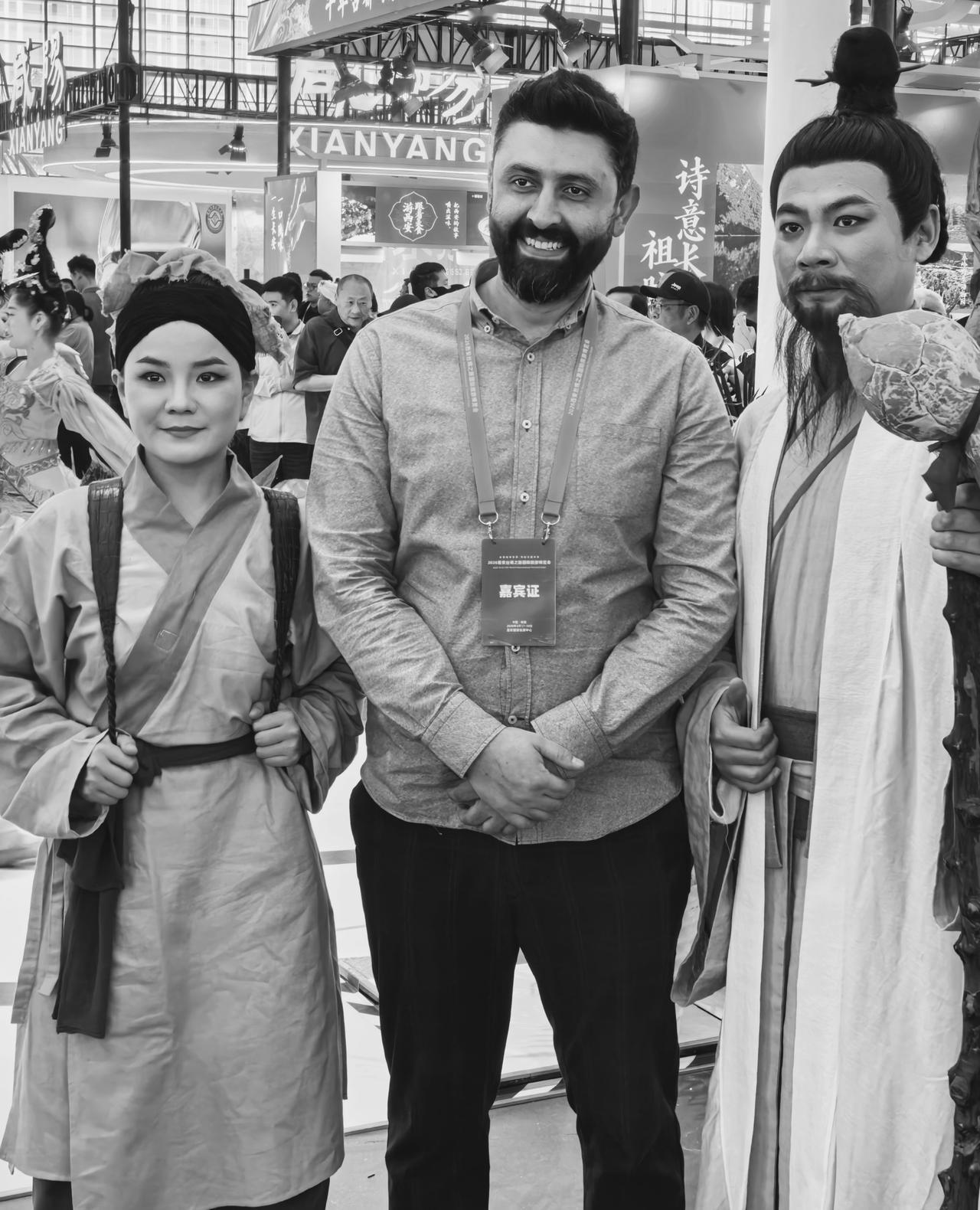 波斯商人与见了唐朝诗人。在西安旅博会上，戴嘉宾证的外国大叔，左边站着梳双丫髻的唐