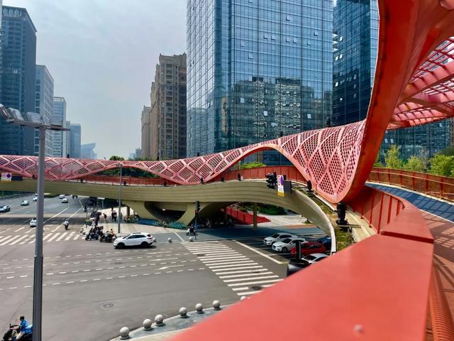 交子大道上的红色天桥，像城市里流动的飘带，将现代高楼与市井烟火温柔相连。在成都的