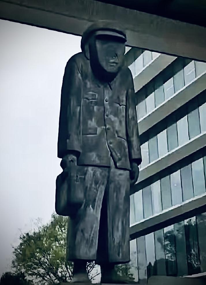 阿里巴巴集团广场南，
有一个佝偻着身子的。
含胸缩脖的无脸丑男。

他一手里提着