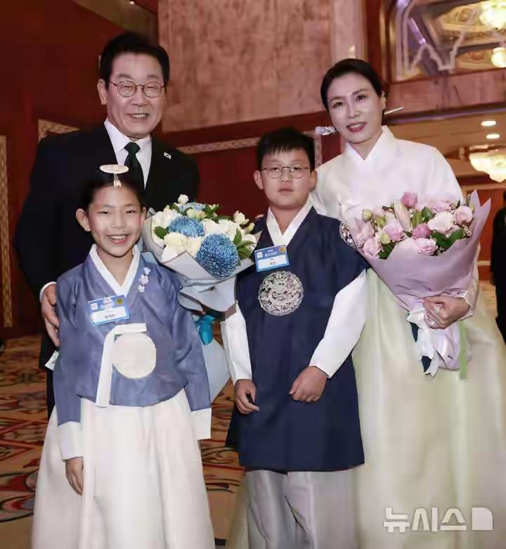 李在明夫妇和韩国小朋友合影，有三人都身着朝鲜传统服，其实他们传统服蛮好看的。要是
