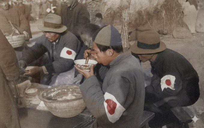 1937年12月15日南京，四五个穿黑色棉袄、左臂佩戴白底红日章臂章的人正蹲在路