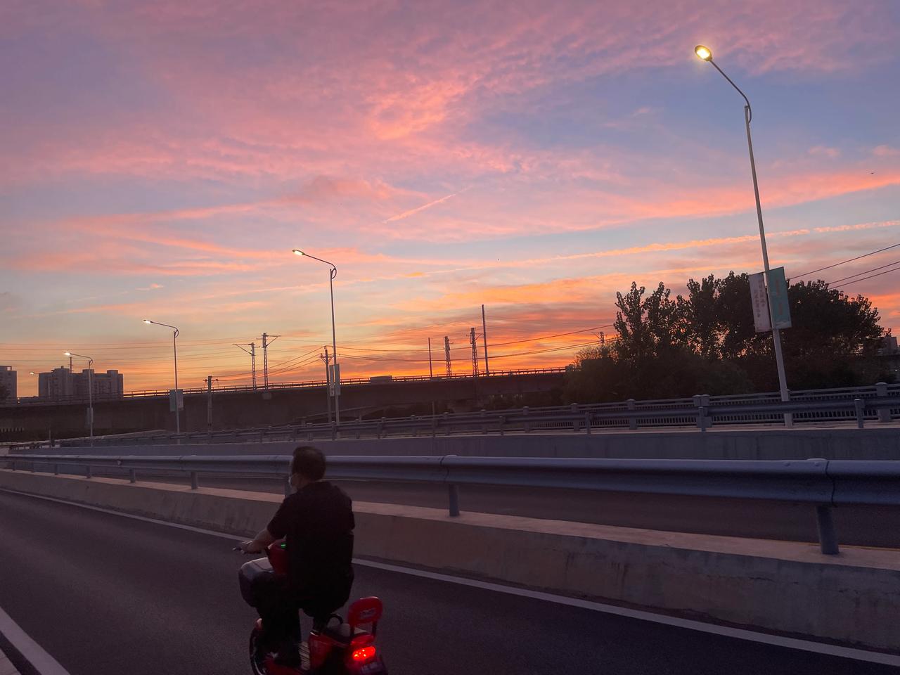 
晚霞下：
一个是骑着摩托车的中年人，一个是骑着自行车的少年。
两人去的方向不同