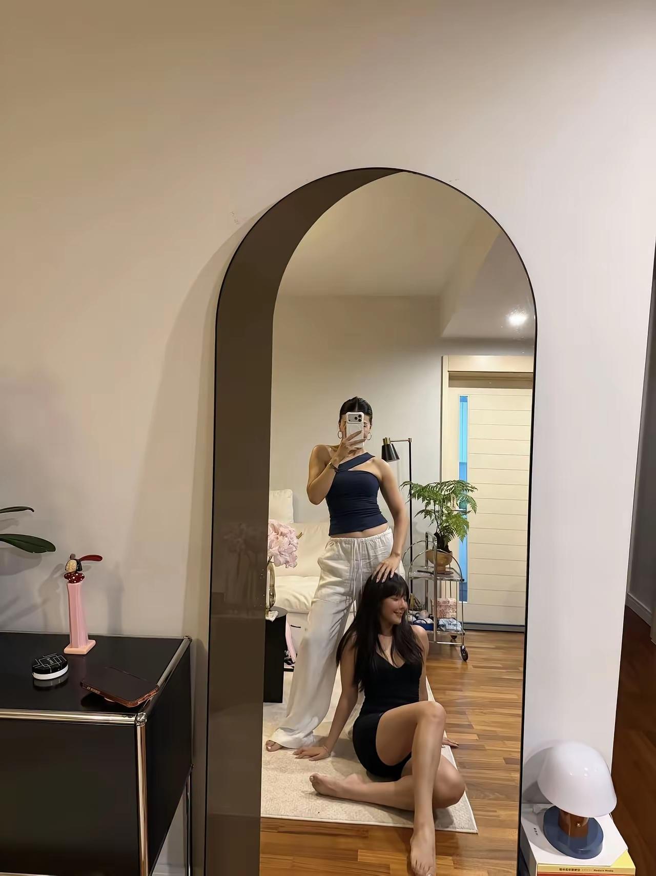 两姐妹在客厅镜子前自拍。