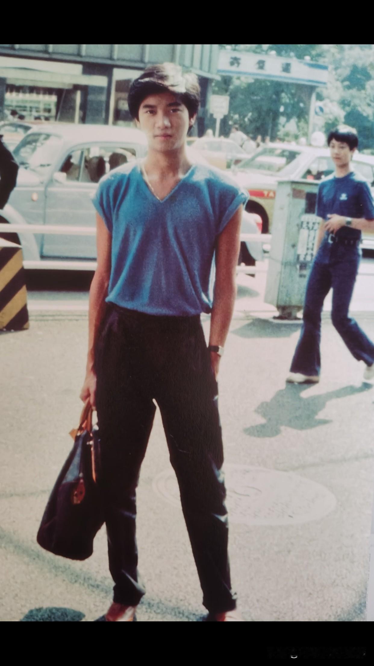 陈百强青春年华～V领无袖蓝衫配黑色阔腿裤，手拎包的松弛感像刚逛完尖沙咀的午后。