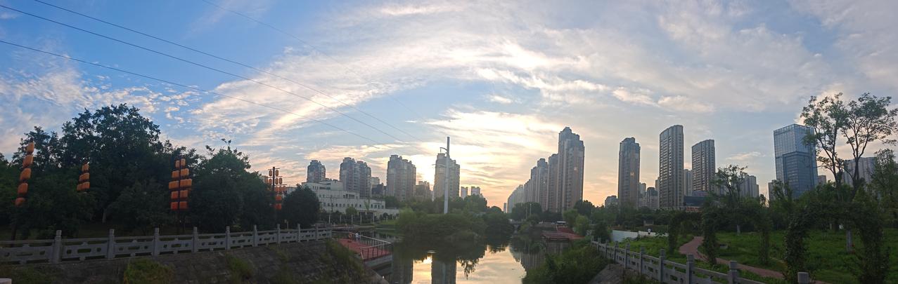 晨光熹微，城市高楼倒映在河面上。