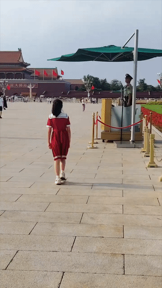 一名红衣小女孩缓缓走到北京天安门执勤哨兵的面前。
她郑重其事的向哨兵行了一个“少
