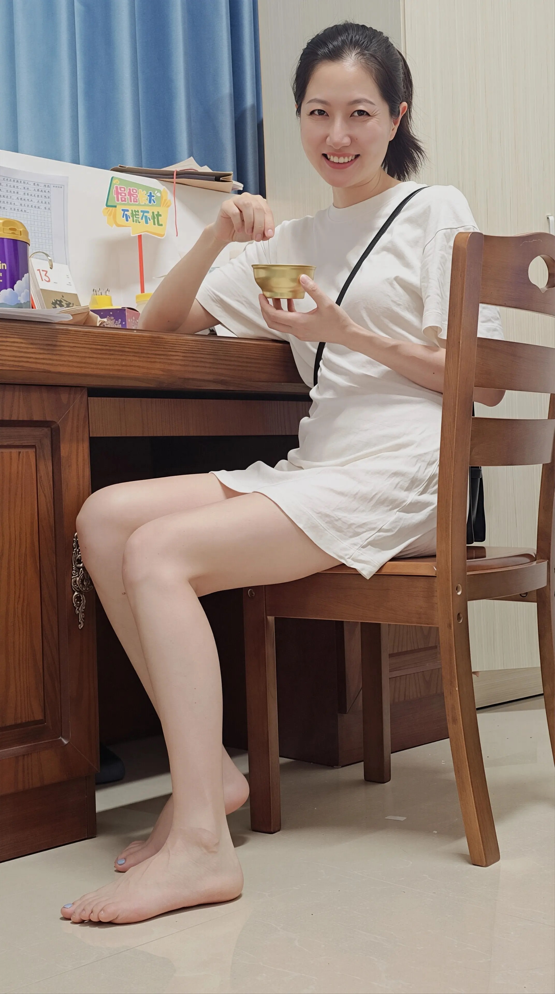 白T恤裙简约舒适，赤脚居家尽显松弛感。笑容灿烂治愈，手持金碗添趣味，慵懒随性风太