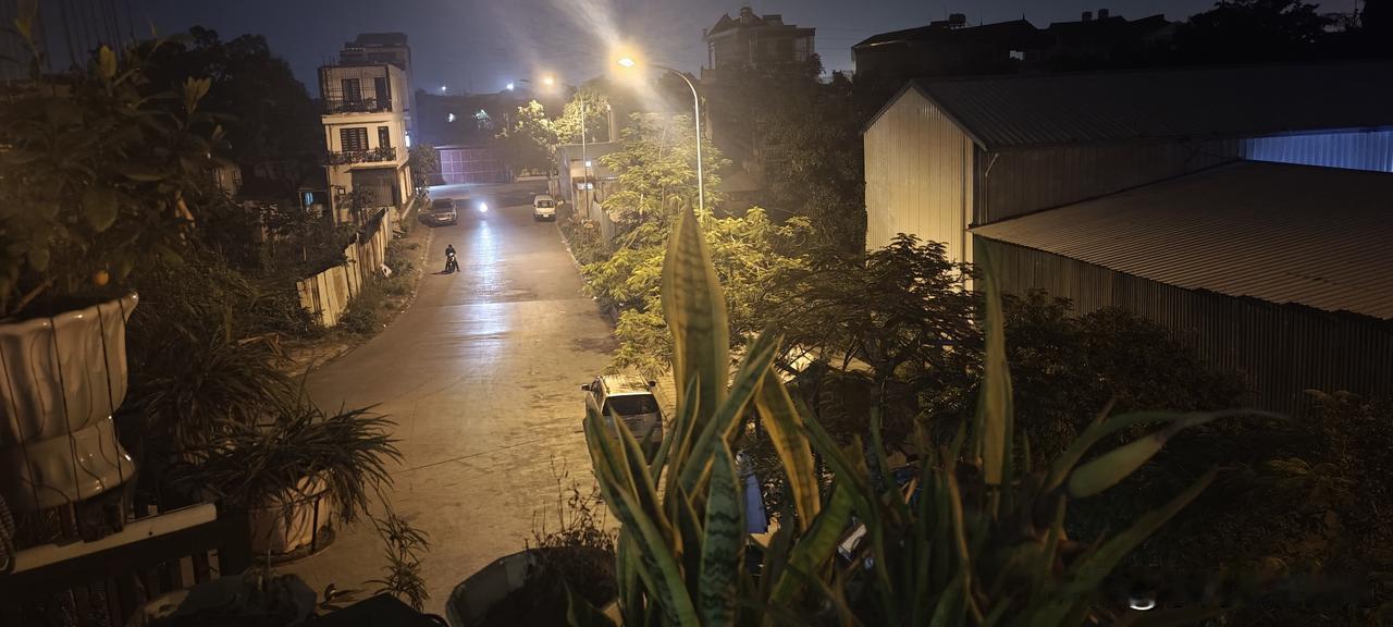 我右手指夹着烟，运动T恤、短裤穿扮站在三楼的阳台上，遥望着远处打着灯的建筑工地。