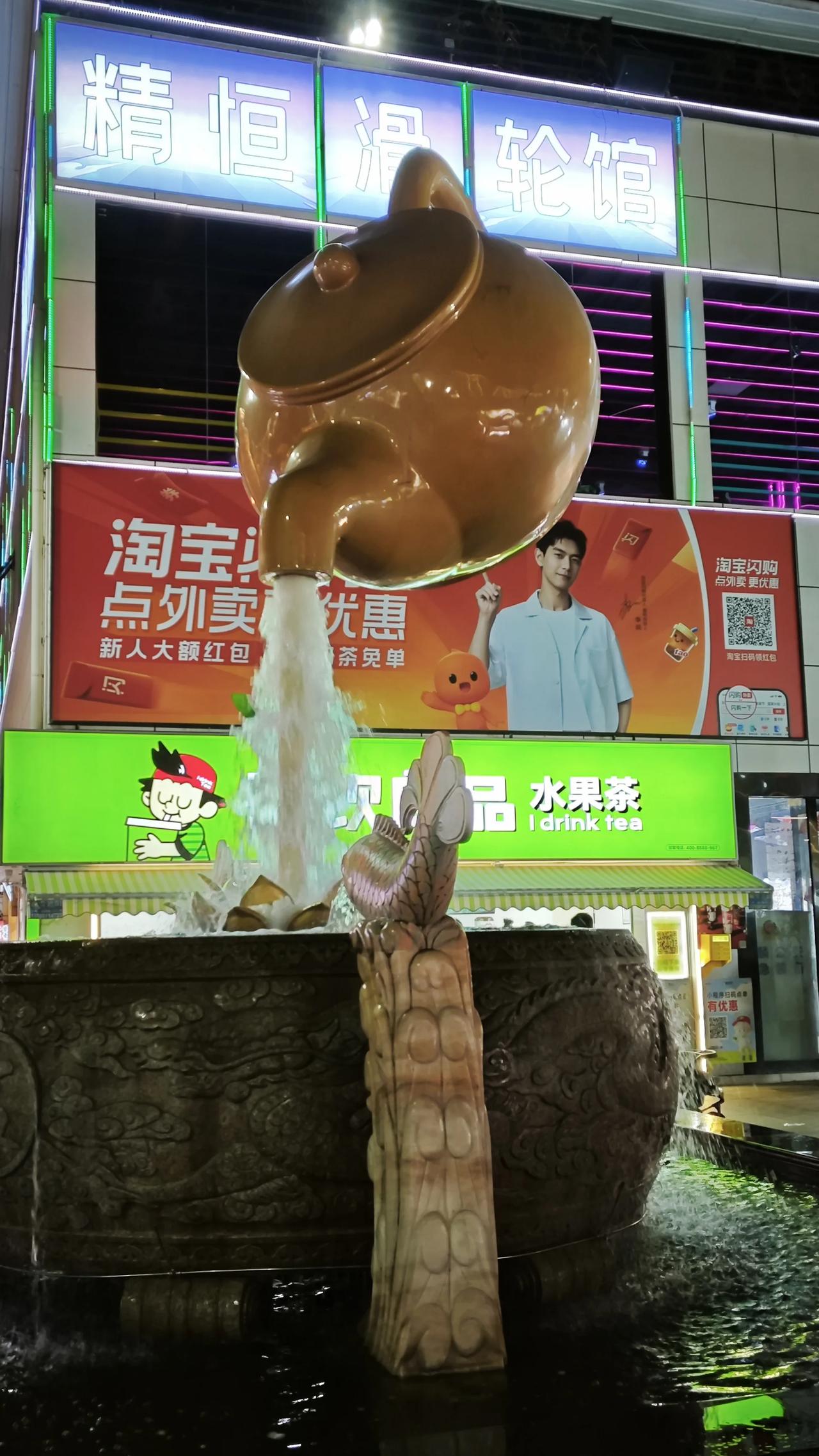 春日生活打卡季夜色里的悬空茶壶，把市井烟火都泡成了温柔。喷泉潺潺，霓虹闪烁，藏着