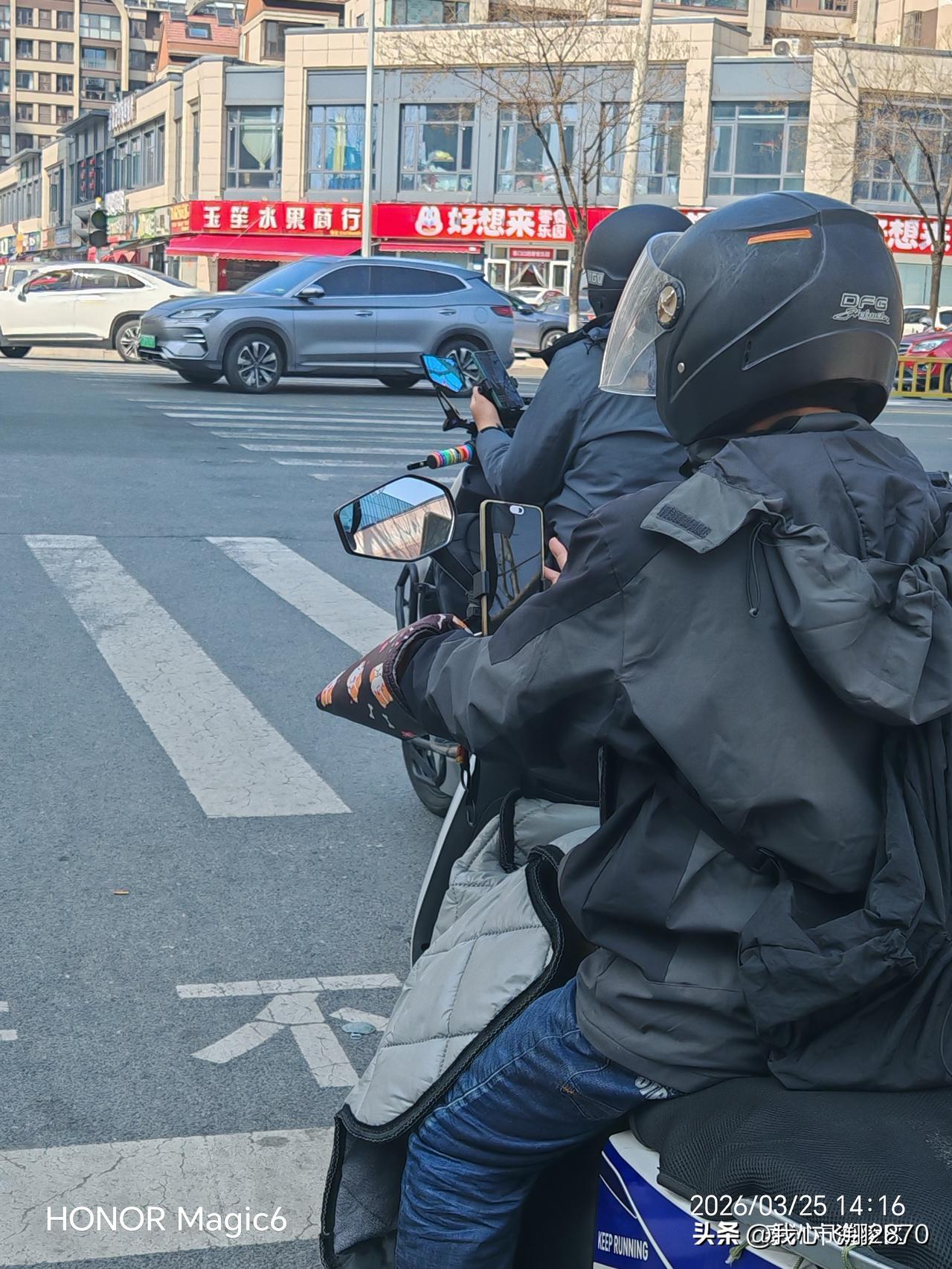 电动车上安装手机支架，骑行过程中还不断看手机短视频，这种做法太危险了，给交通安全