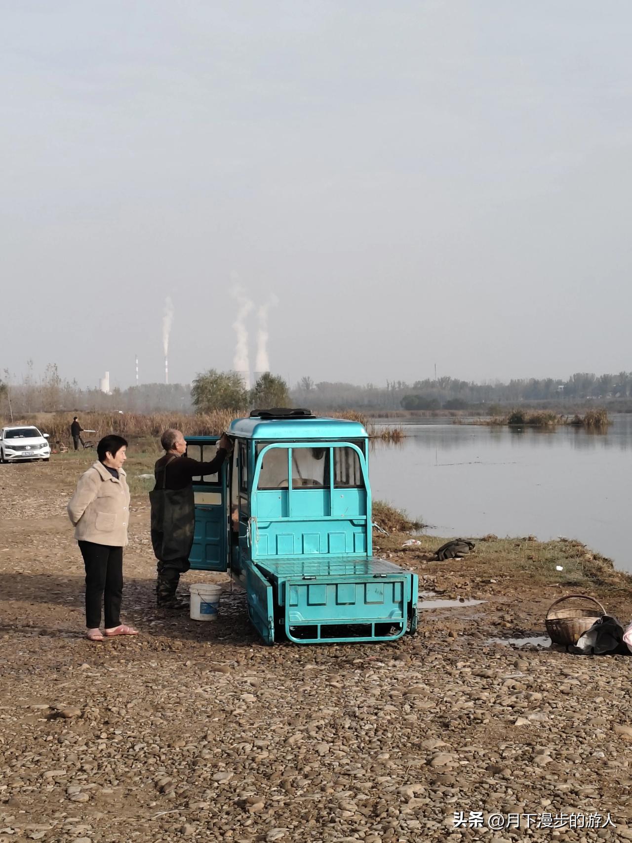 今天跟着老伴来河边，他穿那身防水裤是要下河摸东西。咱那小蓝电三轮往岸边一停，还怪