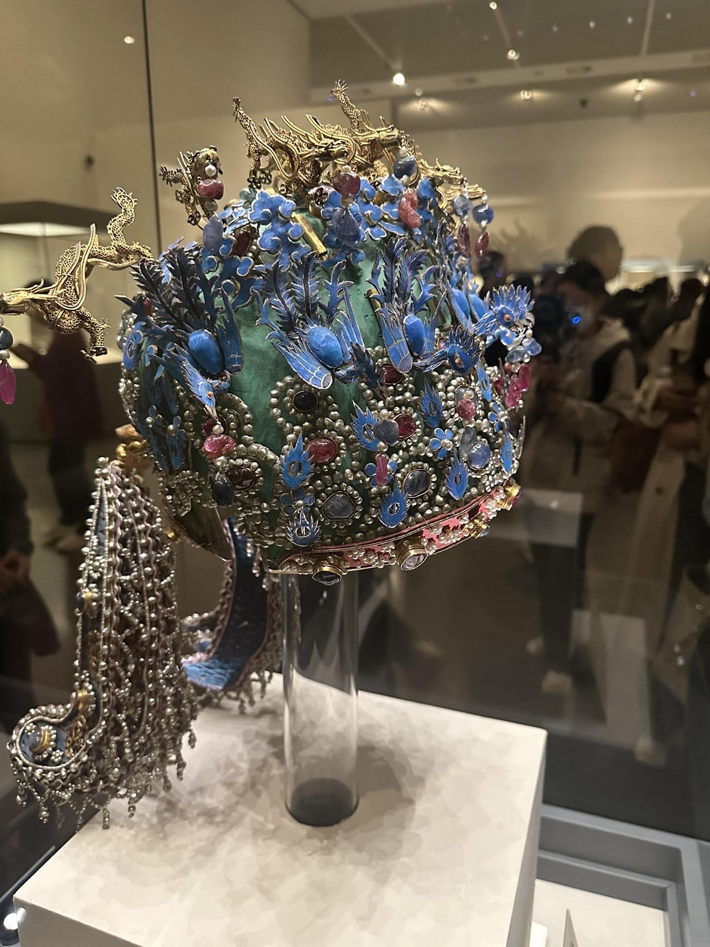 明•孝端皇后九龙九凤冠
该冠通高48.5厘米、冠高27厘米、径23.7厘米，重2320克。用漆竹扎成帽胎，面料以丝帛制成，前部饰有九条金龙，口衔珠滴，下有八只点翠金凤，后部也有一金凤，共九龙九凤。冠上共嵌未经加工的天然红宝石115块，珍珠4414颗。