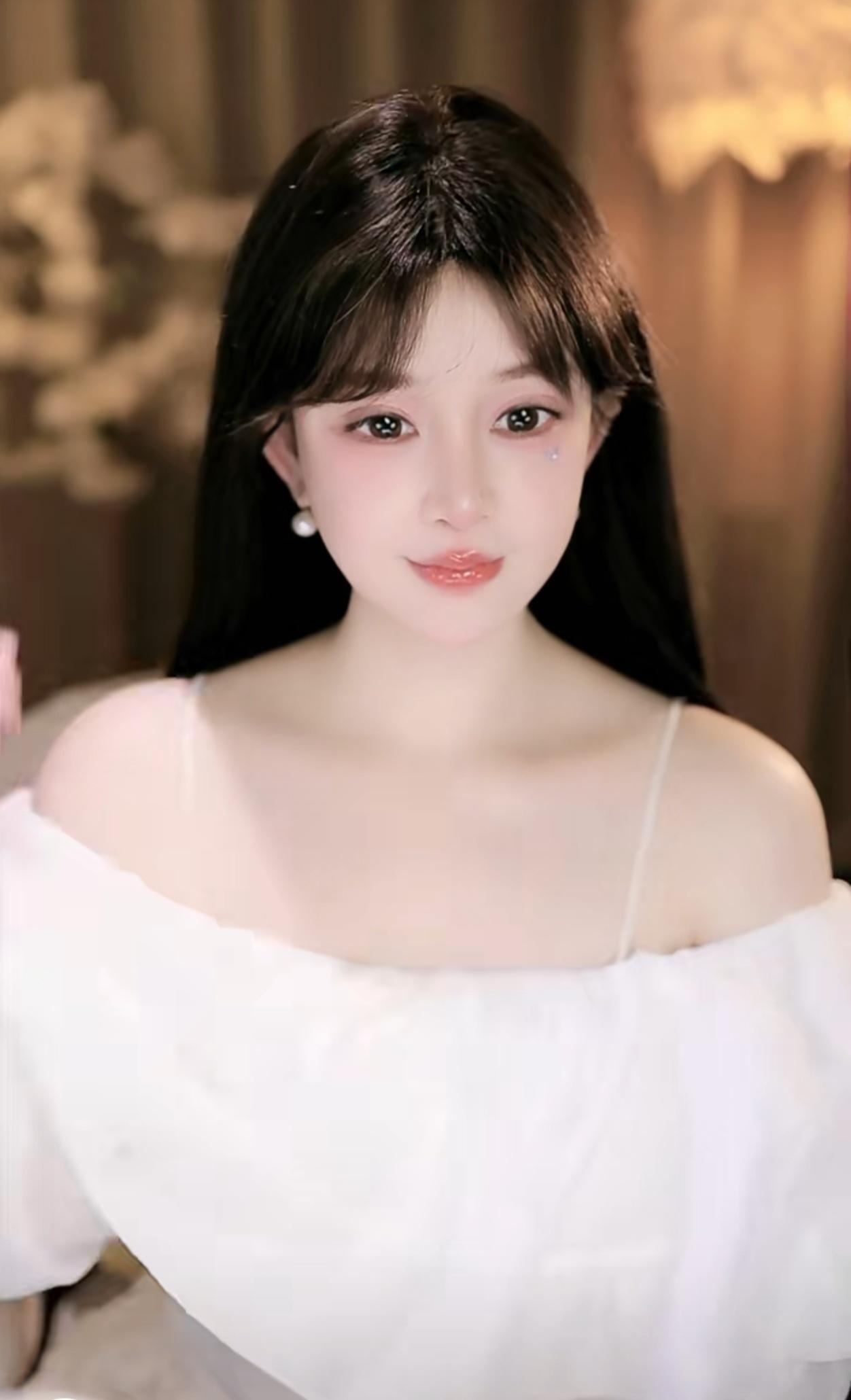 她留着一头乌黑柔顺的长直发，空气刘海衬得脸庞愈发小巧精致。肌肤白皙胜雪，眉眼清澈