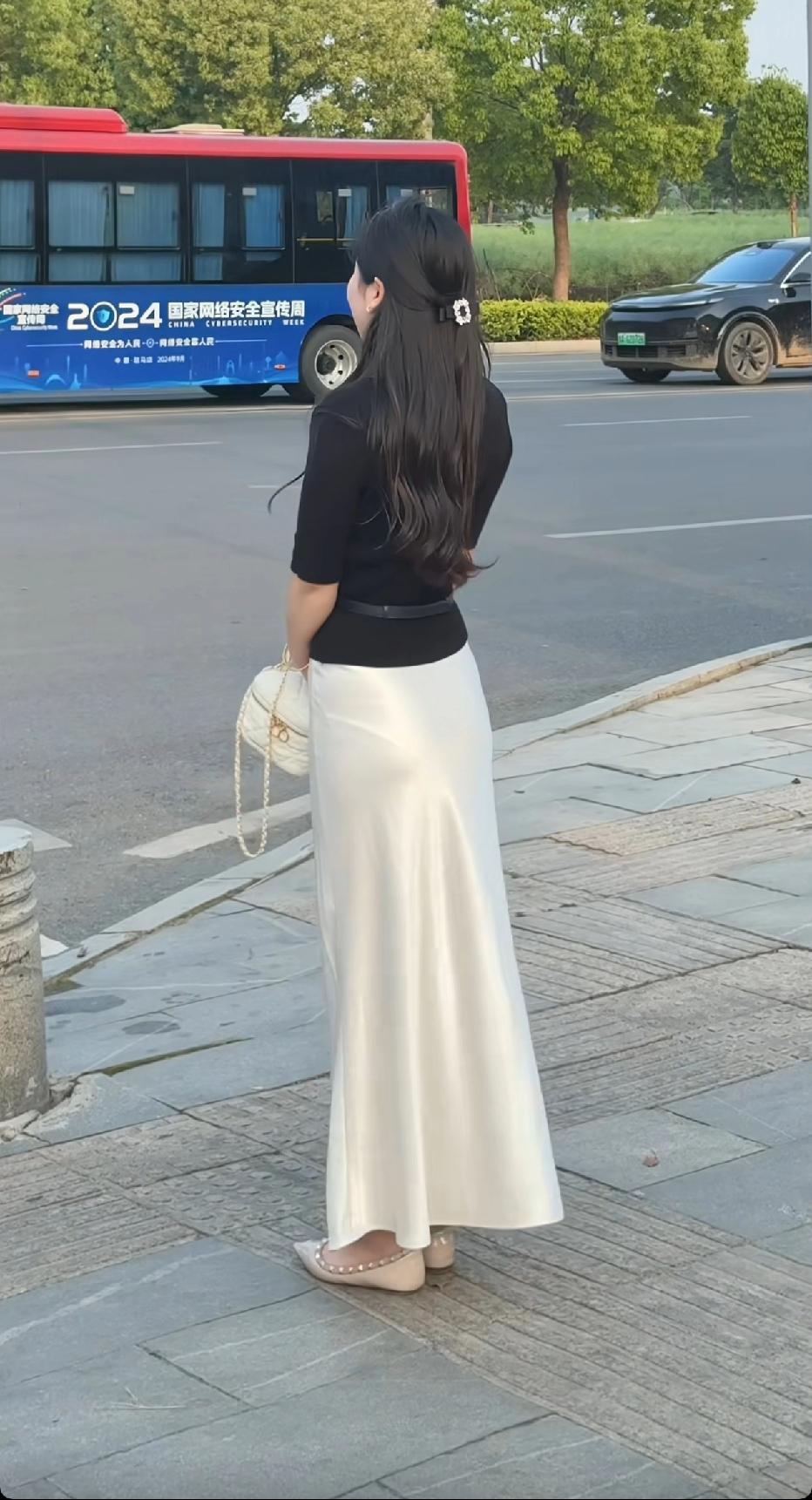 一位长发美女在路边等车。