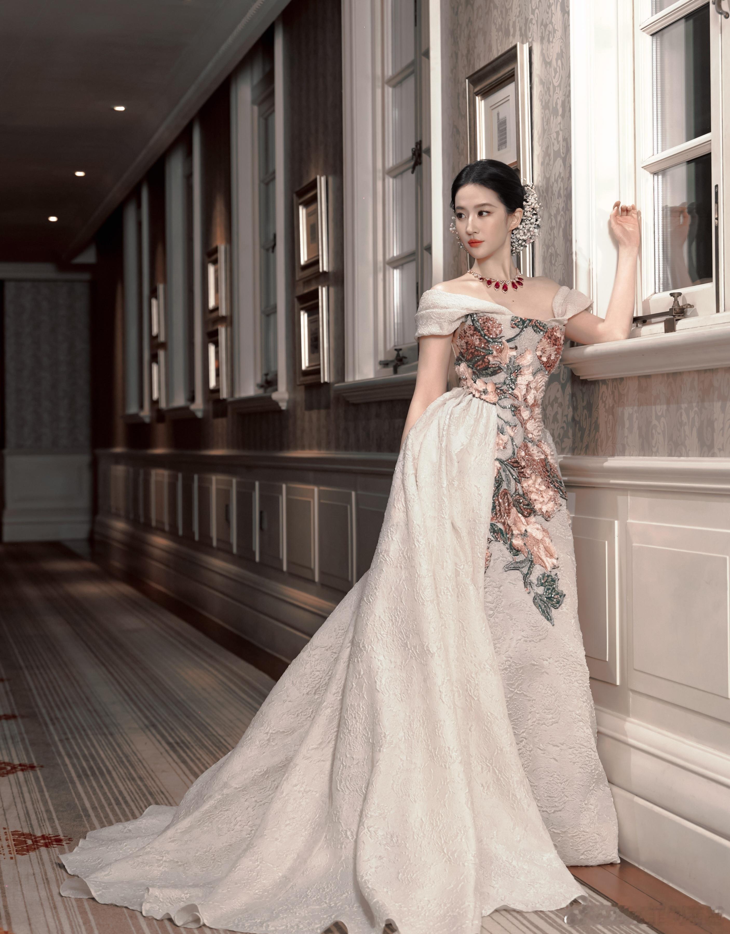 刘亦菲这次身着一袭米白色提花一字肩拖尾礼裙，裙身立体提花面料尽显高级质感，胸前与