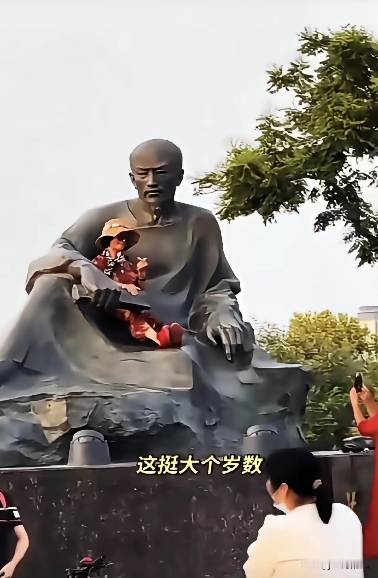 大妈这是什么操作？钻进雕塑的怀里拍照，这要是脚底一滑摔下来，那可真是“老太太钻被