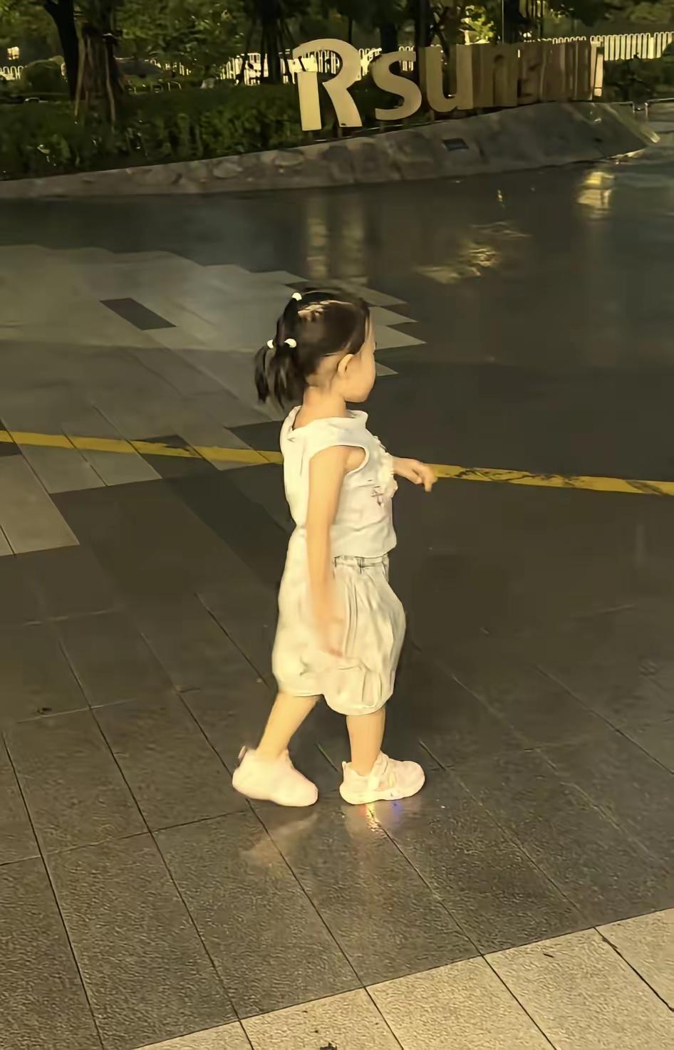 闪闪在雨里跳着舞，满是快活劲儿。闪闪如今三岁四个月啦，正站在姥姥家门前的小广场上