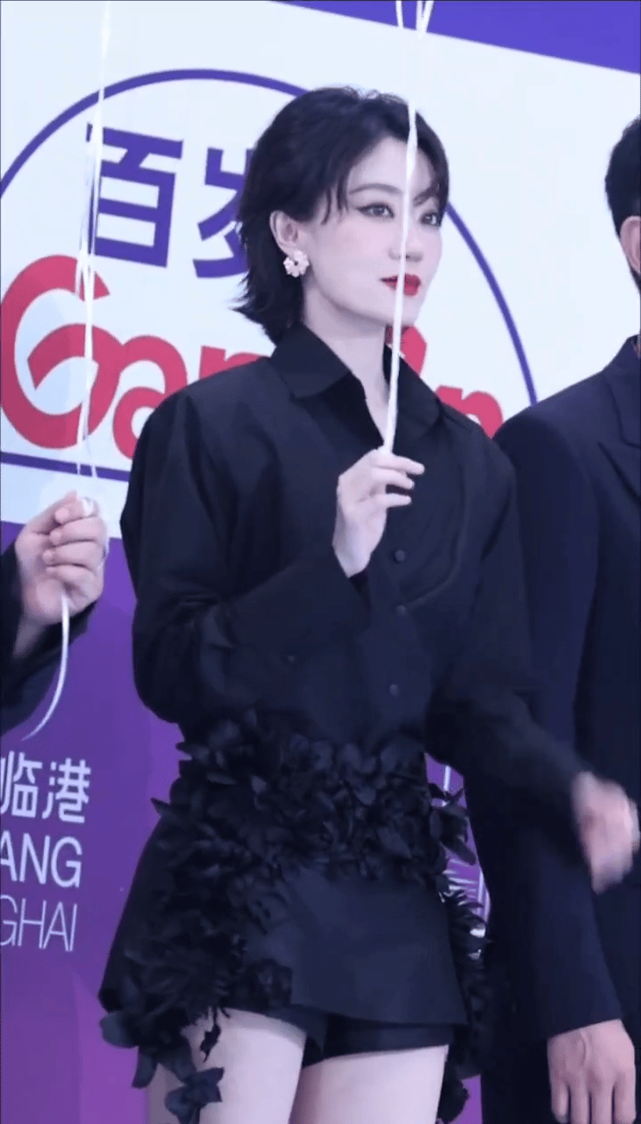 张小斐身着黑色衬衫加同色短裤，酷帅尽显。精致五官在黑衣映衬下更显冷艳，气质卓然。