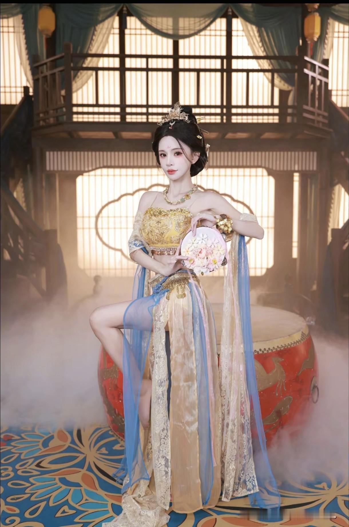 身着金蓝华裳倚鼓而立，手持团扇笑靥如花。这穿越千年的盛世美颜。红墙映华裳 唐装团