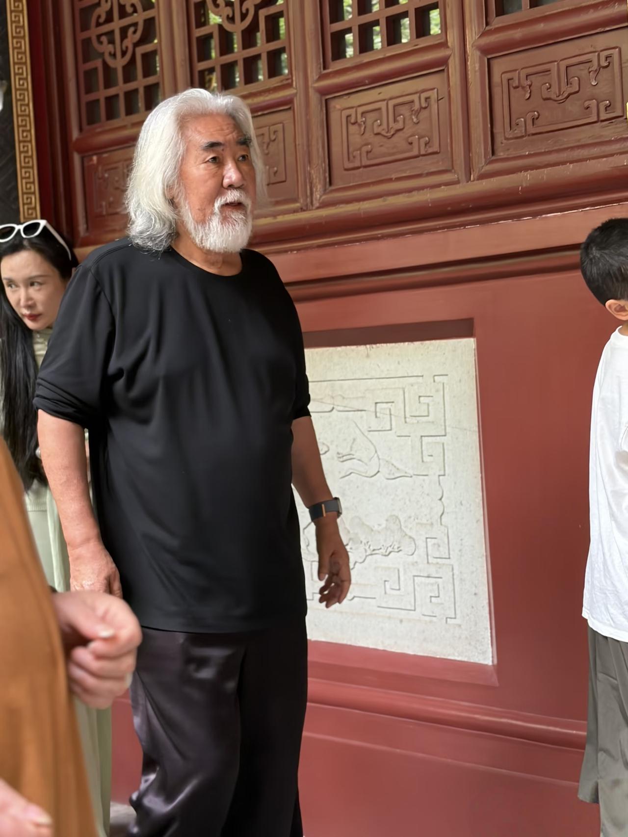 75岁张纪中和老婆杜星霖带四个孩子现身浙江大佛寺祈福，他穿着一身黑衣，满头白发，