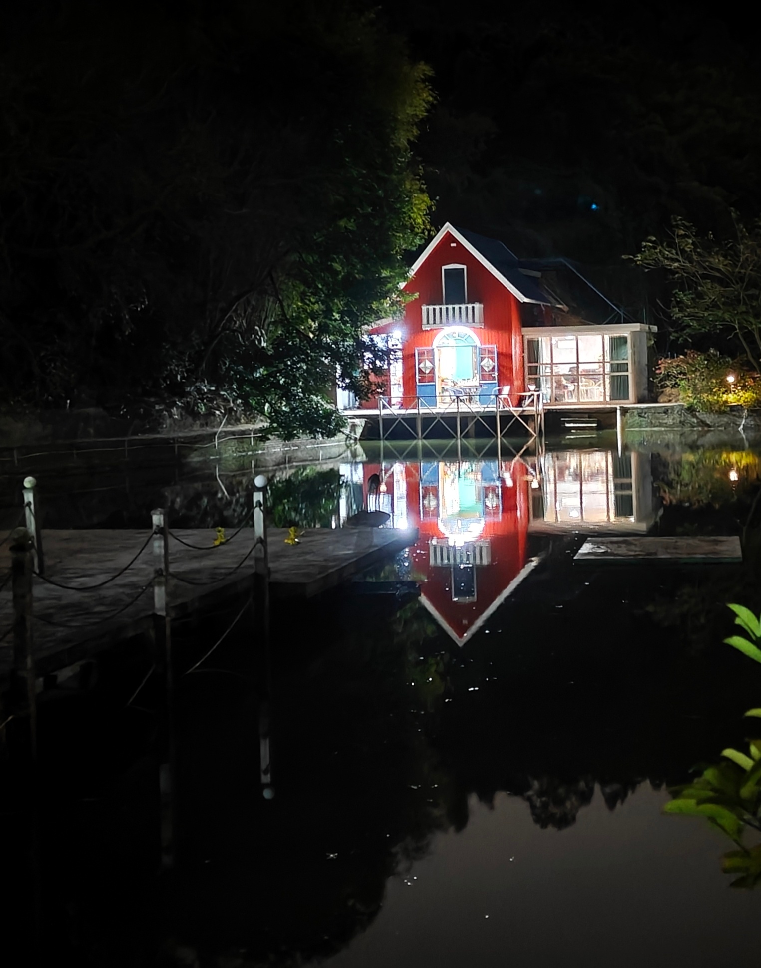 夜色中，一座红色小屋静静立于水边，灯光温馨，倒影如画。它提醒我们，在忙碌生活中，