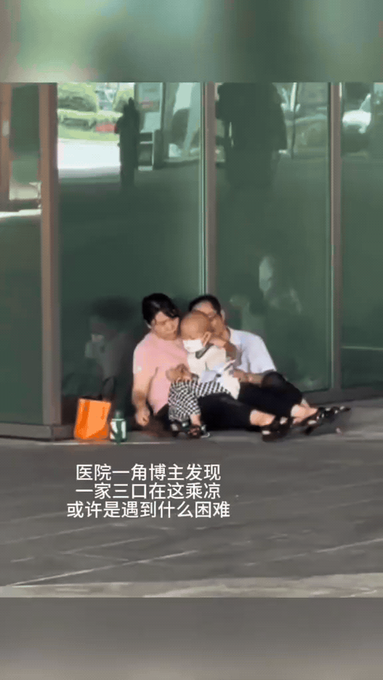 医院门口的一张照片，暖哭无数人
 
医院的玻璃门旁，一家三口席地而坐，妈妈紧紧抱