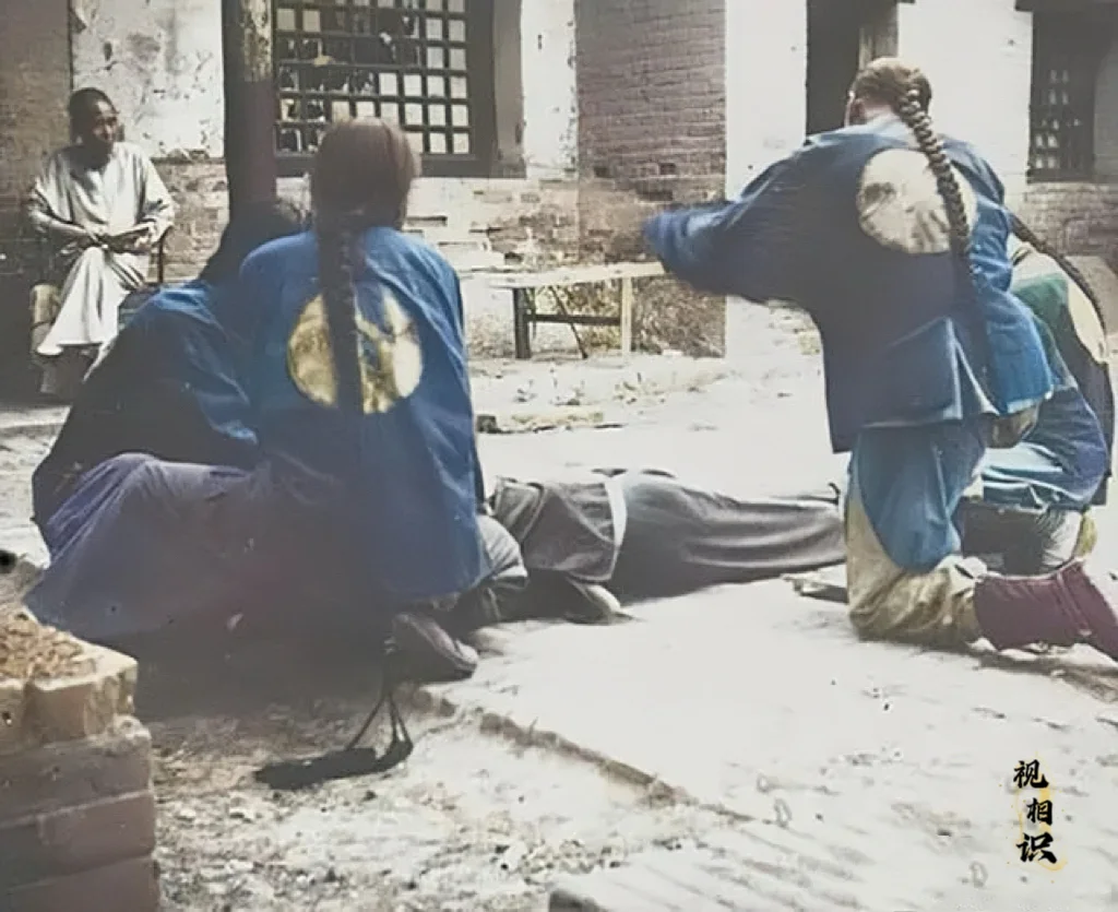 清末时期，一名男子正在被衙役“打板子”，在影视作品里面，经常会说将犯人...