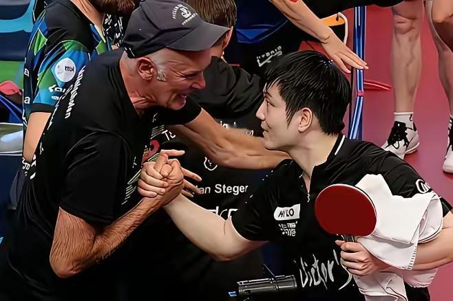 樊振东在德国打完比赛后，没急着回休息室，而是径直走向观众席前排。一位头发花白的德