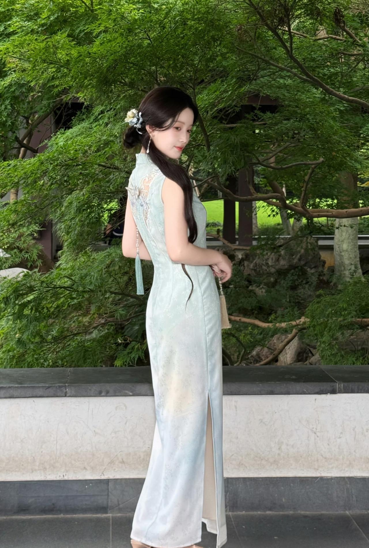 漂亮女生身着带有月神蛾刺绣元素的渐变蓝绿色旗袍，外搭温柔的米白色薄纱披肩，长发搭