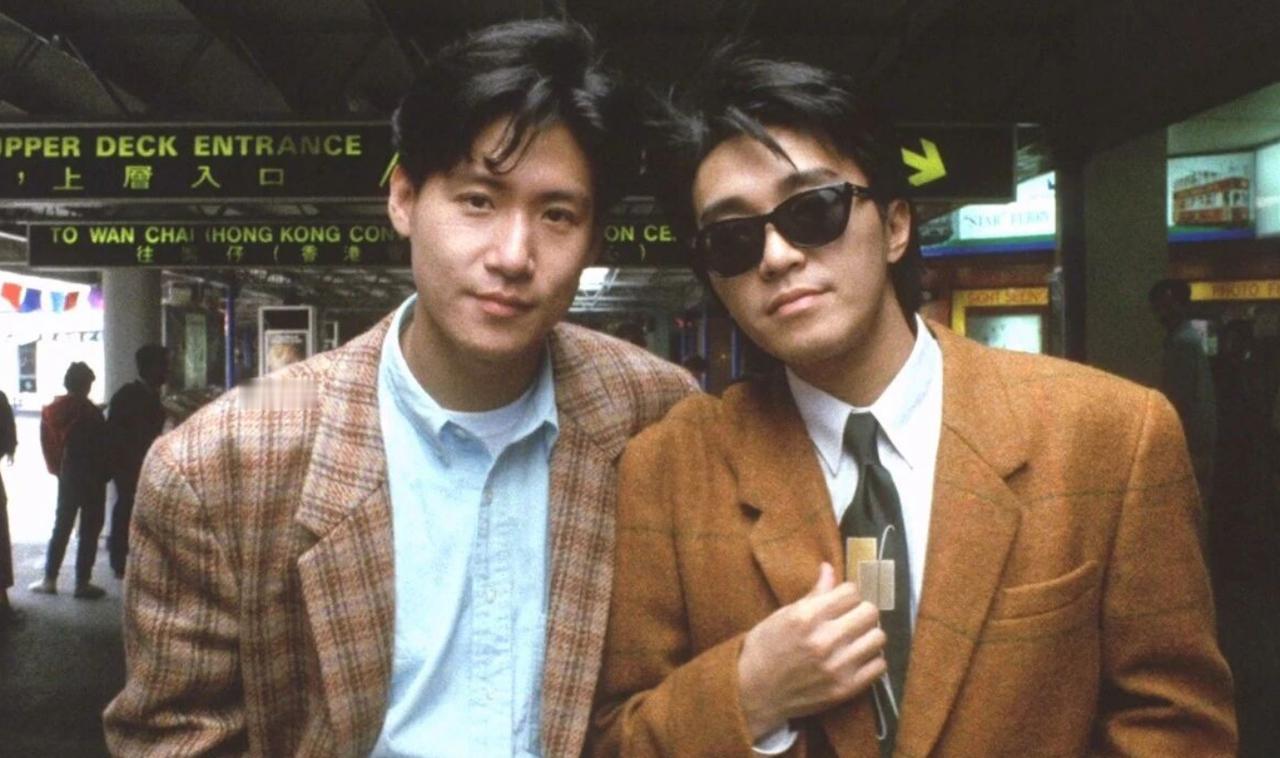 一张老照片，定格 1990 年《咖喱辣椒》片场瞬间。
 张学友与周星驰并肩站在香