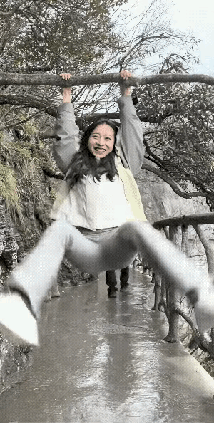性格开朗活泼的女生，伸出双臂，双手紧握住上面的树枝，把身体悠了起来，看来玩的很开