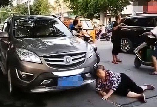 谁的锅？辽宁一大妈打算碰瓷豪车，但是车主等红绿灯时熄火低头玩手机，并没有注意到。