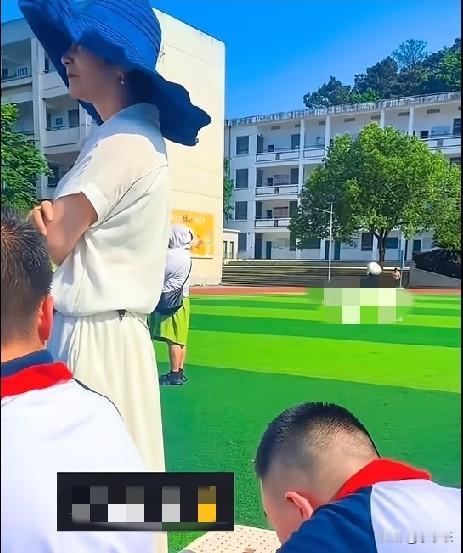 近日，湖南一小学学生在操场上观看“六一”演出，一男孩看到老师一直站着，默默地小心