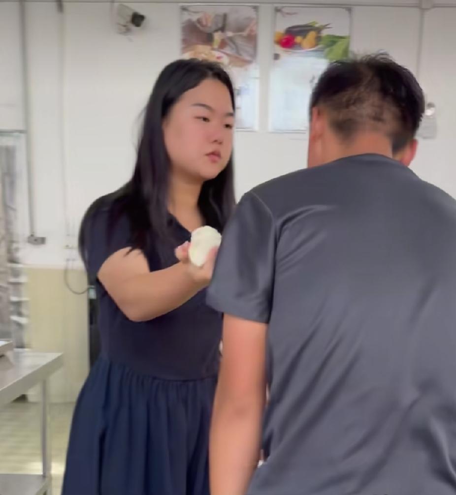 学生食堂里，正在吃饭的一名学生男孩，突然起身走到老师面前，红着脸给老师鞠躬行礼，