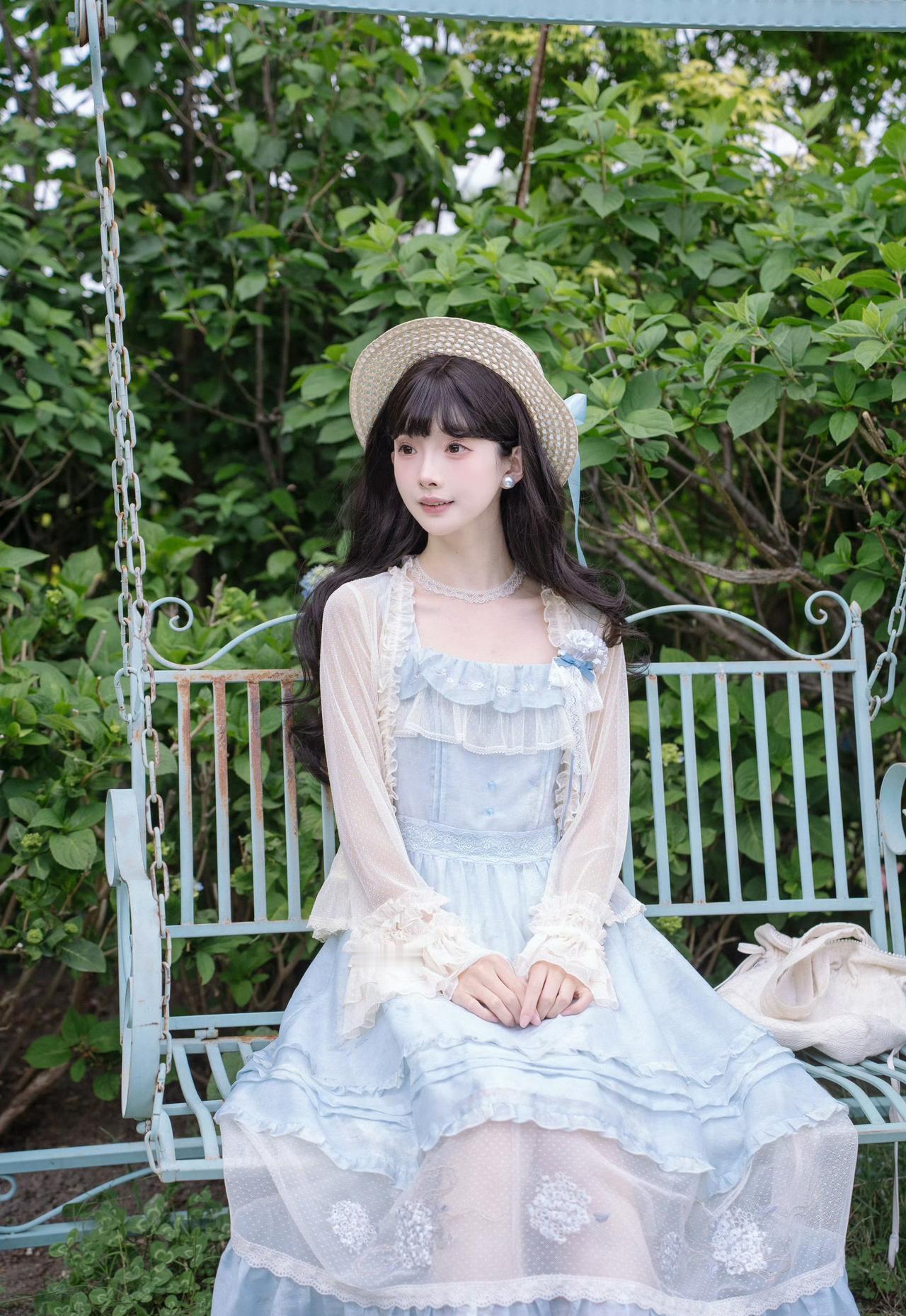 浅蓝裙裾漫过初夏的花园，草帽轻挽温柔日光。

风携着草木与花香漫来，裙边蕾丝随步