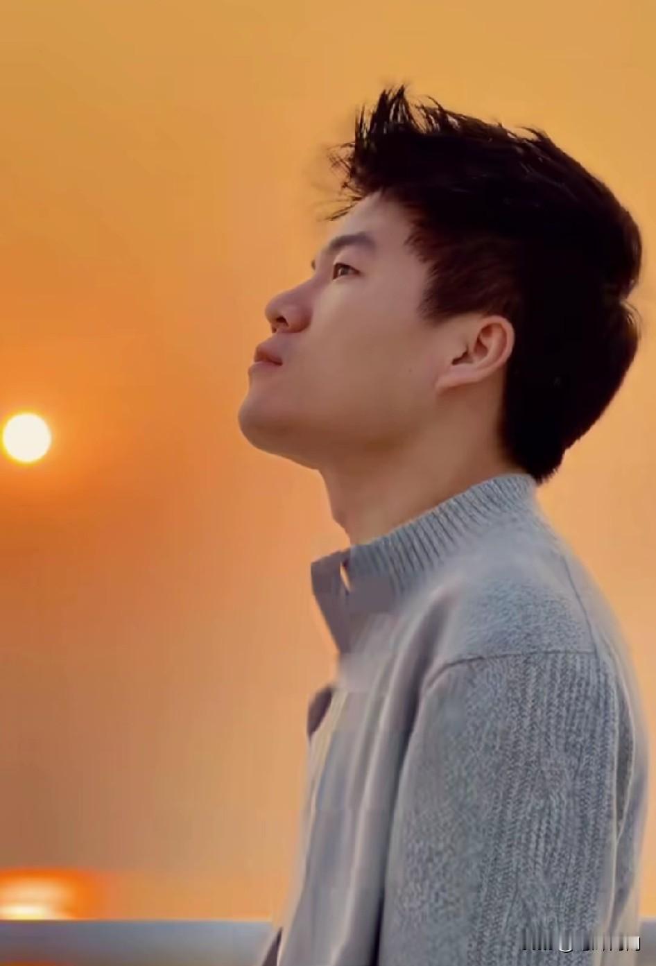 感董宇辉在落日的海边，默默感受落日余晖，被海风吹起的毛衣，肆虐的在胸前飞舞着，就