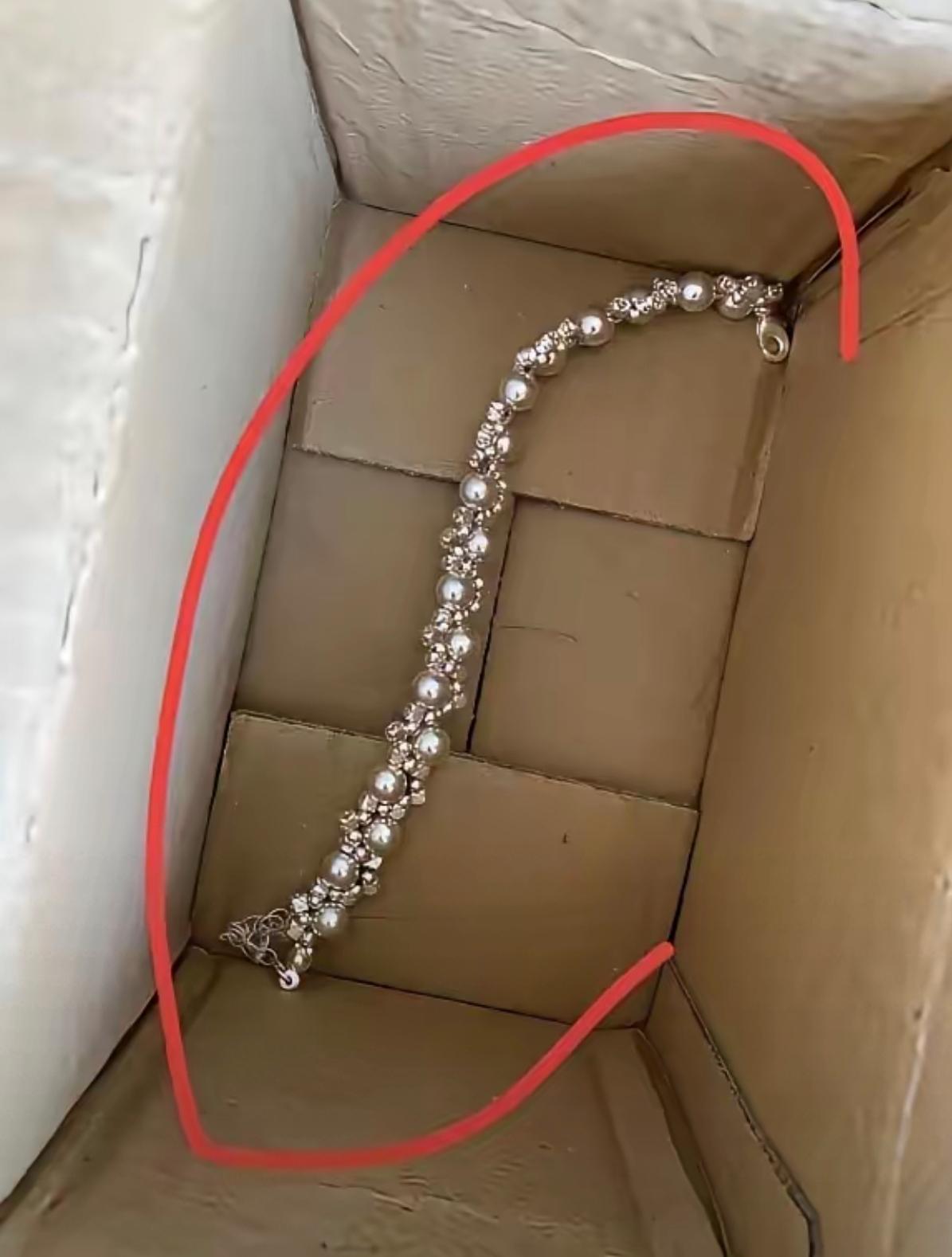 一个珍珠手链放在纸盒里，包装很简单。