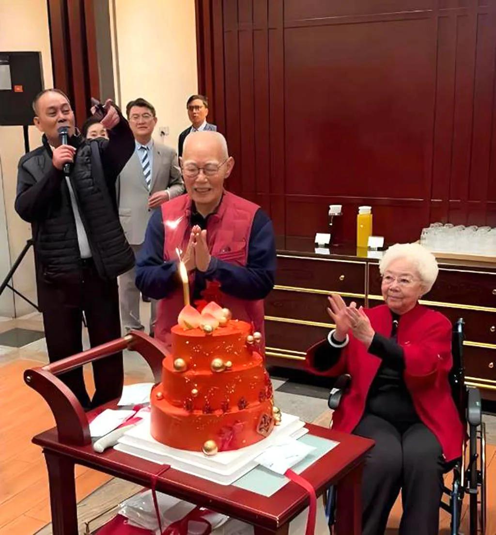 这张照片记录了张勇手老师91岁寿辰的温馨时刻：身穿红色马甲的张勇手气色盈和，双手