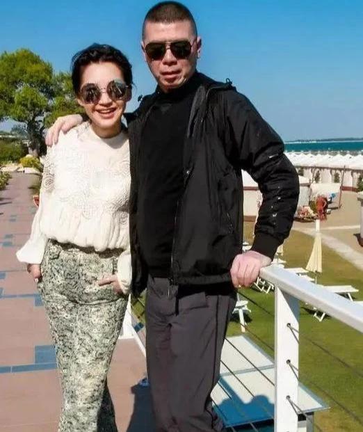 冯小刚和许晴当年在国外游玩时留下的合影照片。冯小刚身穿黑色上衣配黑色外套，戴着墨